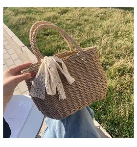 Detail of straw beach tote with woven handles and a decorative white lace ribbon bow