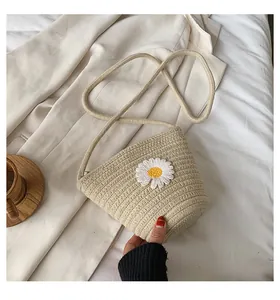 Gros plan détaillé du sac bandoulière en paille avec broderie de marguerite blanche