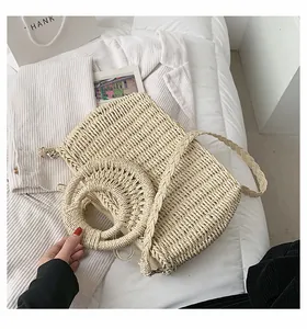 Dettaglio della borsa in paglia intrecciata a mano con manici tondi e fodera interna beige