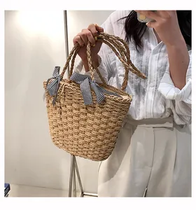 Dettaglio borsa tote in paglia con trama intrecciata e fiocchi a quadretti bianchi e neri
