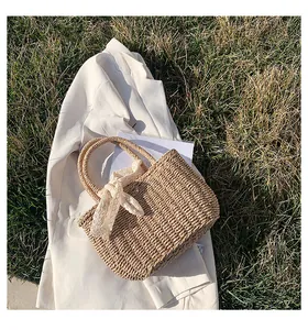 Detailed texture of hand-woven straw beach bag with circular handles and lace ribbon