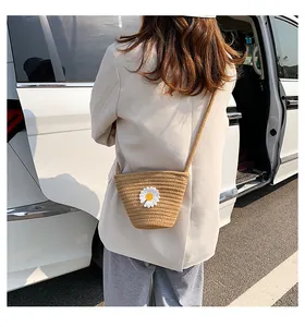 Détail d'un petit sac seau en paille avec broderie marguerite sur matière tissée kaki clair
