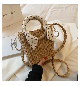 Detailed close-up of woven straw handbag with decorative scarf and shoulder strap detail