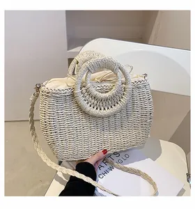 Dettaglio borsa in paglia intrecciata a mano con manici tondi e fodera beige