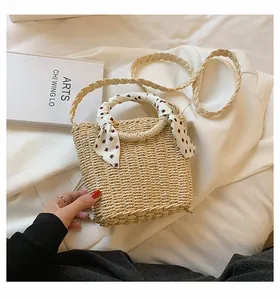 Detail of woven straw handbag featuring a decorative silk scarf and matching shoulder strap