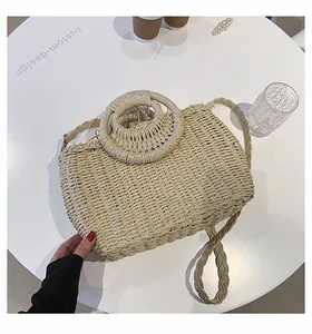 Dettaglio della borsa in paglia intrecciata con manici rotondi e tracolla a treccia fine
