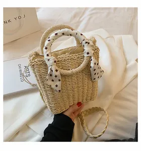 Detail of woven straw bag with decorative silk scarf handle and drawstring closure
