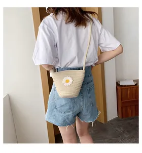 Détail du sac seau en paille crème avec applique marguerite et bandoulière élégante