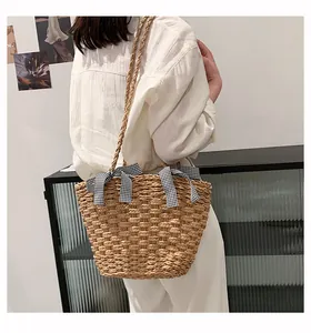 Dettaglio della borsa da spiaggia in paglia intrecciata a mano con fiocchi a quadretti decorativi