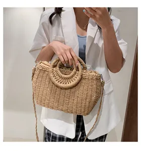 Dettaglio della borsa in paglia intrecciata con manici tondi e coulisse su blazer bianco