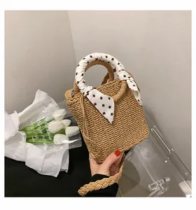 Detail of straw woven bag featuring a stylish plaid scarf-wrapped handle for beach vacations