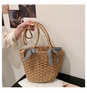 Dettaglio della borsa in paglia intrecciata con fiocchi a quadretti bianchi e neri e coulisse