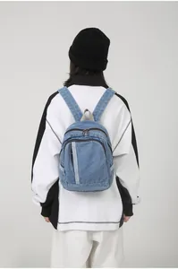Detail achteraanzicht van een lichtblauwe denim mini rugzak gedragen door een model