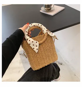 Detail of beige straw bucket bag featuring woven texture and silk scarf handle decoration