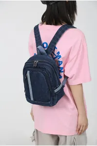 Detail van de mini blauwe denim rugzak met zilveren ritsen en contrasterende stoffen band