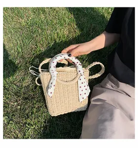 Detail of straw handbag with woven round handles and a red polka dot silk scarf wrap