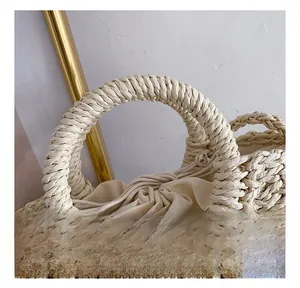 Close-up of woven straw handbag featuring sturdy round handles and a drawstring pouch
