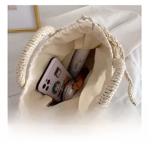 Detail view of woven straw handbag interior with drawstring lining and daily essentials