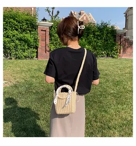Detail of straw woven bag with white polka dot scarf handle on a sunny lawn
