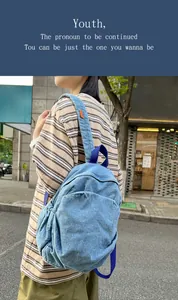 Foto de estilo callejero de mochila denim azul lavado con etiqueta naranja y bolsillo con cremallera