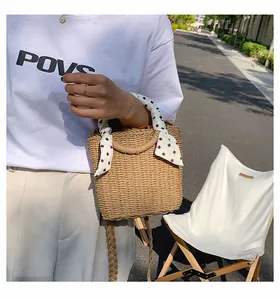 Detail of woven straw box bag with printed silk scarf handle and braided strap