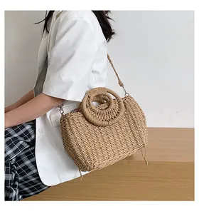 Dettaglio borsa in paglia intrecciata con manici rotondi e lacci decorativi lunghi