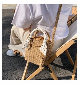 Detail of straw bucket bag with silk scarf handle and yellow drawstring lining