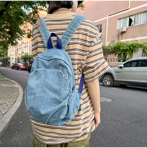 Detalle de una mochila vintage de mezclilla azul desgastada usada por una modelo afuera