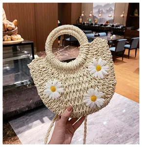 Detail of handmade straw bag featuring white 3D daisies and circular woven handles