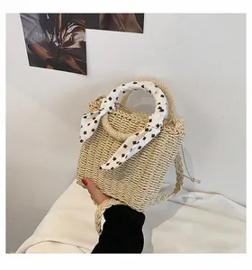 Detail of light beige straw bucket bag featuring a red checkered scarf and drawstring closure