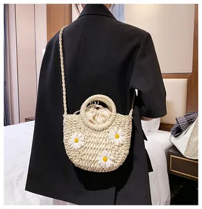 Straw bag with daisy applique and drawstring lining worn cross-body over black jacket