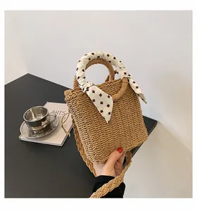 Detail of hand-woven straw bag with red diamond pattern silk scarf wrapped on handle