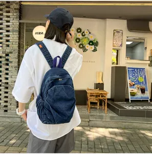 Detalle de mochila de mezclilla lavada azul oscuro con bolsillos laterales en un modelo
