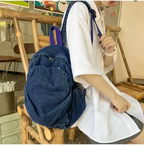 Detalle de mochila de mezclilla lavada con correas púrpuras en modelo en una cafetería