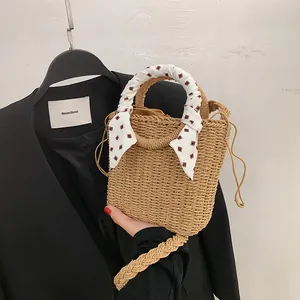 Handmade woven straw bucket bag with scarf-wrapped handle and drawstring lining for beach