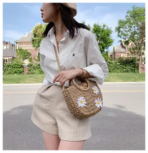 Straw crossbody bag with white daisy flowers shown in a summer vacation street style