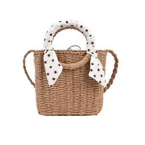 Natural brown straw woven handbag with patterned silk scarf for summer beach vacation