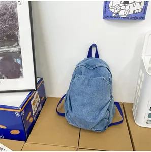 Detalle de mochila de mezclilla azul lavada con cremalleras metálicas y textura frontal