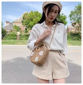 Detail of hand-woven straw bag with white daisy floral accents and drawstring inner pouch