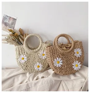 Close-up of semi-circle straw handbags with daisy decor and secure drawstring lining