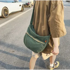 Detail einer dunkelgrünen Segeltuchtasche mit orangefarbenem Etikett auf Straßenhintergrund
