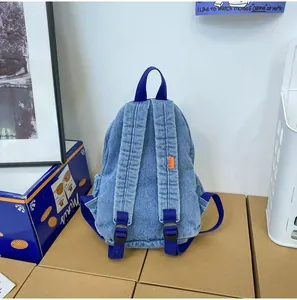 Detalle de la espalda de mochila de mezclilla con correas de nailon y etiqueta naranja