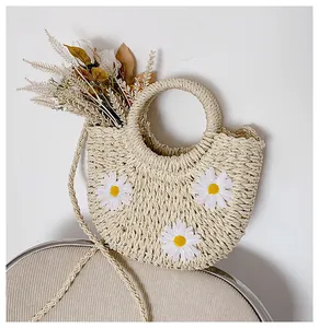 Detailed view of handmade woven straw bag with daisy accents and circular handle