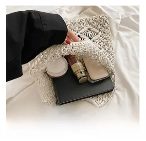 Détail de l'intérieur d'un sac en coton tressé avec anses rondes en bois et objets