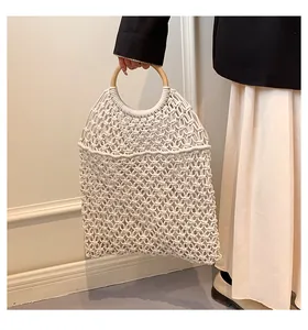 Détail de la texture florale ajourée et de l'anse ronde en bois sur un sac en coton tissé
