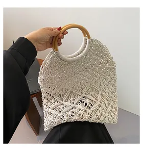 Gros plan du sac à main beige en coton tressé avec motifs noués et anses rondes en bois
