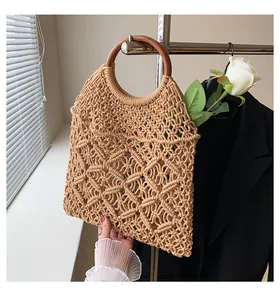 Détail du sac en coton tressé avec des anses rondes en bois sombre et une décoration de rose