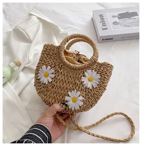 Detail of straw basket bag with white daisy decor and secure drawstring lining