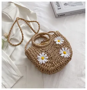 Straw bag detail with 3D daisy flowers, woven handles and brown drawstring lining