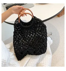 Détail du sac à main en macramé noir avec poignées rondes en bois sur un bureau blanc